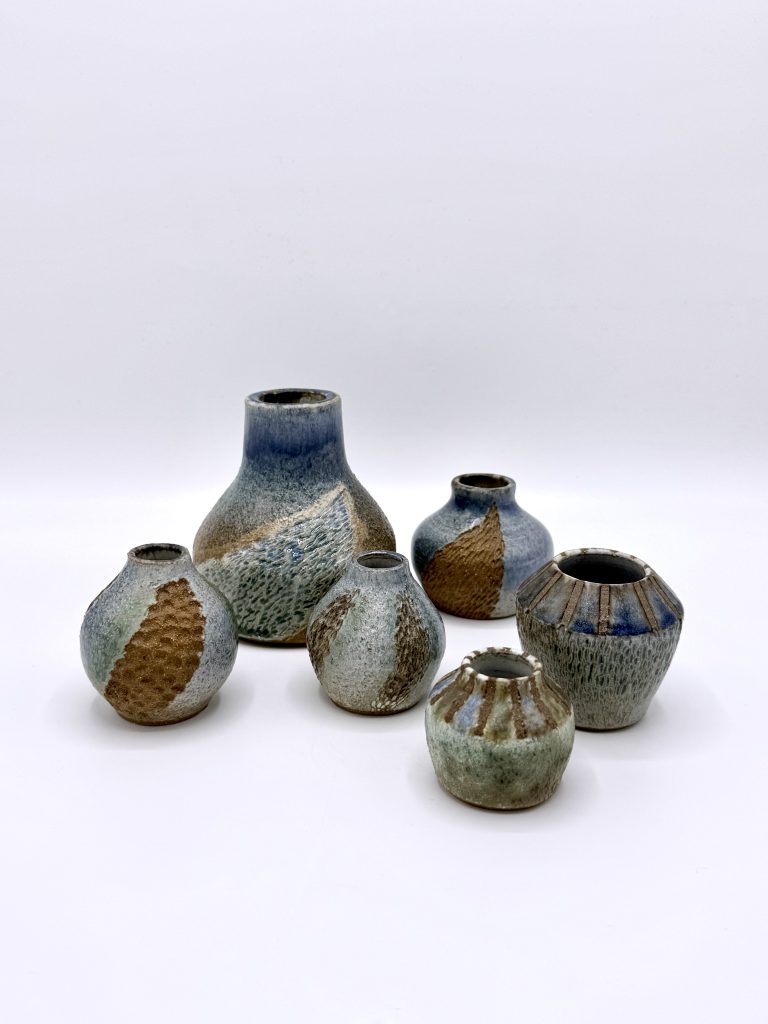 Six handmade ceramic vessels in various forms and spaces, showing a mix of blue, green and brown glazes.