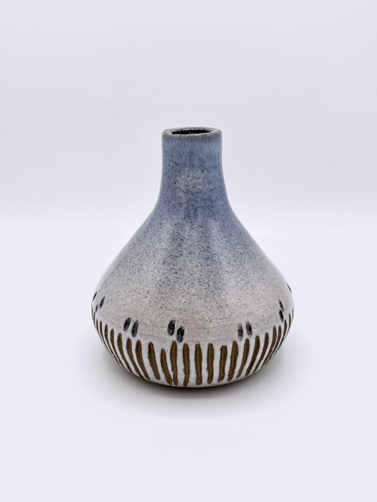 A large blue-and-white ceramic vase with carved vertical channels on a white background.